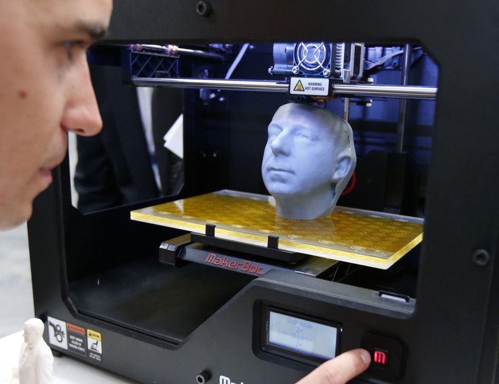 Manuel Leute poses for the media as he uses the 3D printer MakerBot Replicator 2 at the CeBit computer fair in Hanover